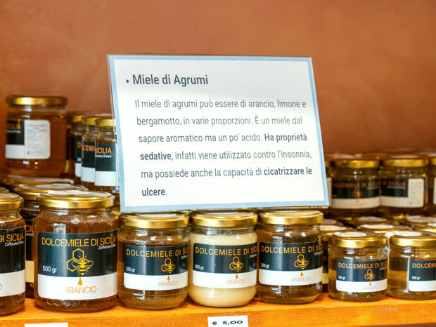 Barattoli di miele di arancio in fila, alcuni liquidi e uno cristallizzato