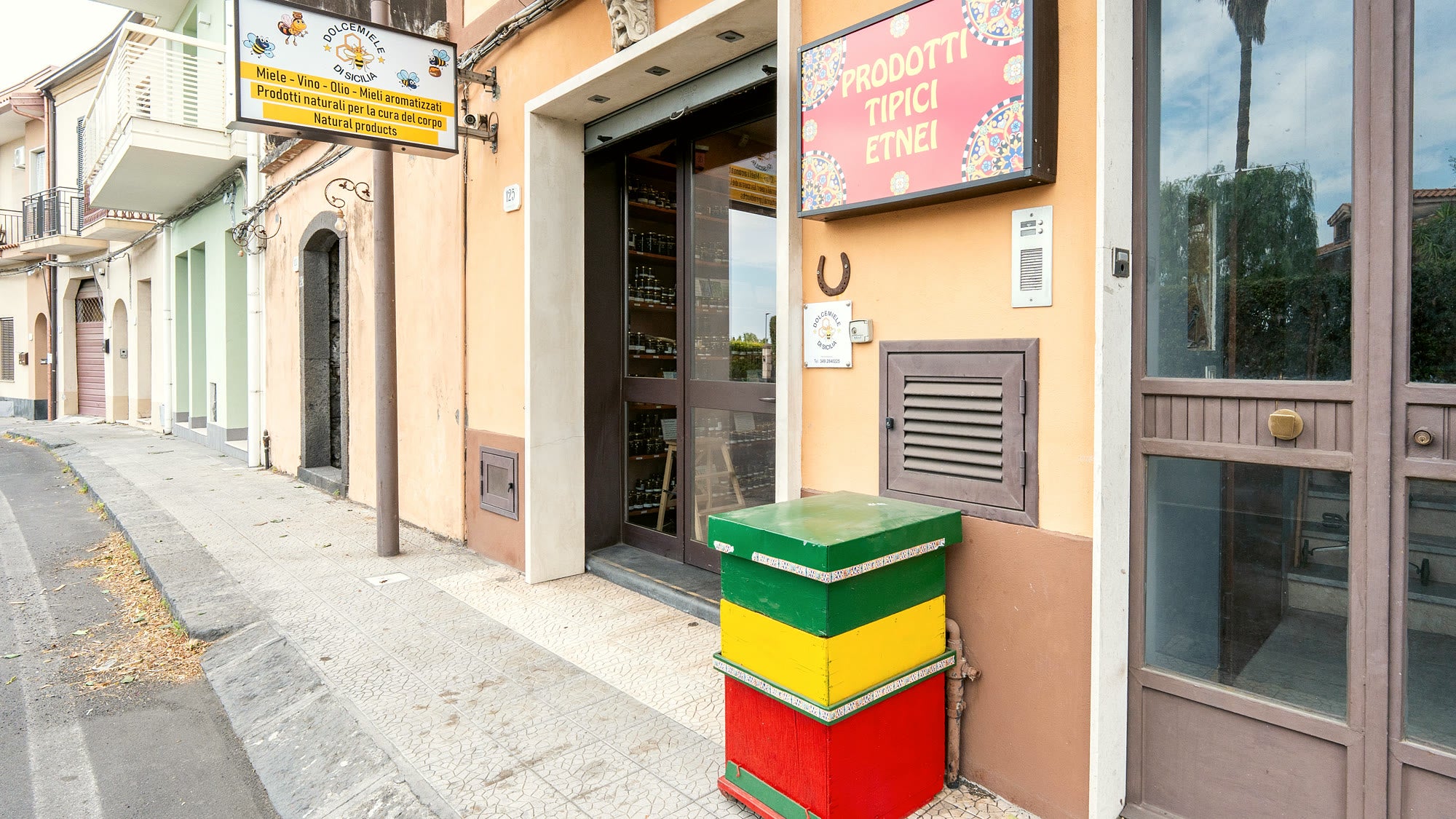 La vetrina della bottega Dolcemiele di Sicilia su strada, con l'arnia colorata sul marciapiede